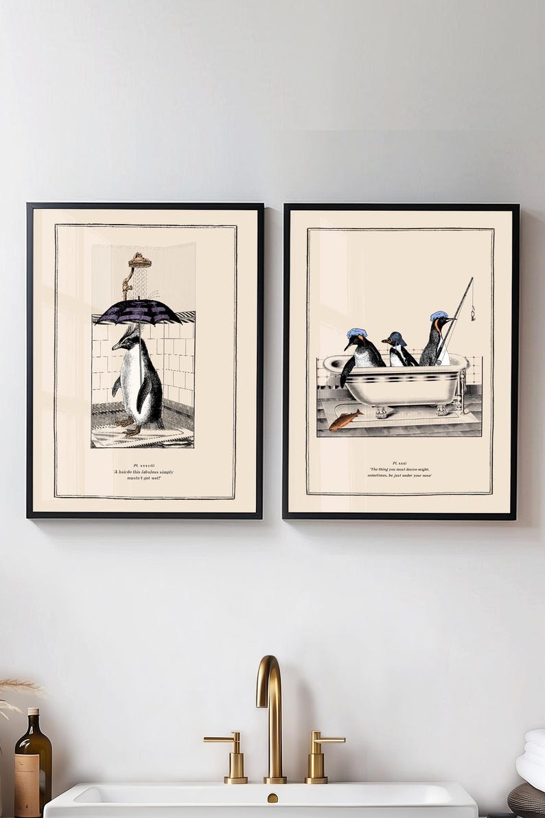 Op de afbeelding: Twee ingelijste kunstprints met pingu&iuml;ns. E&eacute;n toont een pingu&iuml;n onder de douche met een paraplu, de andere pingu&iuml;ns in een badkuip aan het vissen. Elke print heeft een zwarte lijst en een cr&egrave;mekleurige achtergrond.