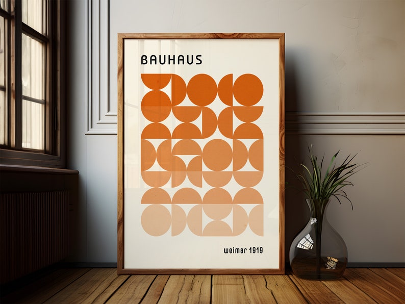 May include: A framed poster with a geometric design in shades of orange. The poster reads "Bauhaus Weimar 1919".