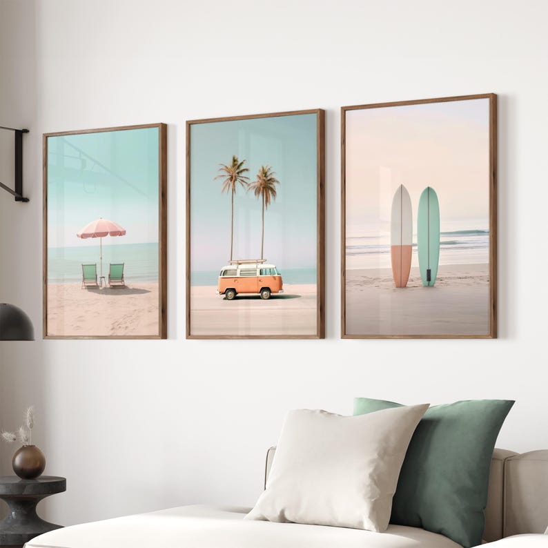 May include: Three framed prints with beach scenes. The first print shows a pink umbrella and two beach chairs on a sandy beach. The second print shows a palm tree and an orange vintage van on a sandy beach. The third print shows two surfboards on a sandy beach.