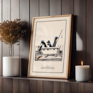 Op de afbeelding: Ingelijste kunstprint met drie pingu&iuml;ns in een badkuip, waarvan &eacute;&eacute;n aan het vissen is. De pingu&iuml;ns dragen blauwe hoeden. De print heeft een licht houten frame en bevat tekst: 'The thing you most desire might, sometimes, be just under your nose.'