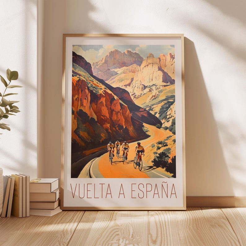 May include: A vintage poster for the Vuelta a Espa&ntilde;a cycling race. The poster features a scenic mountain road with cyclists riding through a canyon. The text "VUELTA A ESPA&Ntilde;A" is printed in red at the bottom of the poster.