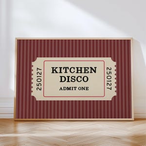 Puede incluir: Una impresi&oacute;n enmarcada con un fondo a rayas verticales burdeos y crema. La impresi&oacute;n presenta un dise&ntilde;o de boleto con las palabras "KITCHEN DISCO ADMIT ONE" en texto negro. El boleto tiene un borde rojo y los n&uacute;meros "250127" a cada lado.