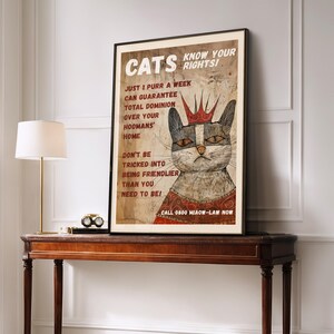 May include: A vintage-style poster with a cartoon cat wearing a crown and a red robe. The poster says "Cats Know Your Rights!" and includes the text "Just 1 purr a week can guarantee total dominion over your hoomans' home. Don't be tricked into being friendlier than you need to be!" and "Call 0800 Miaow-Law Now."