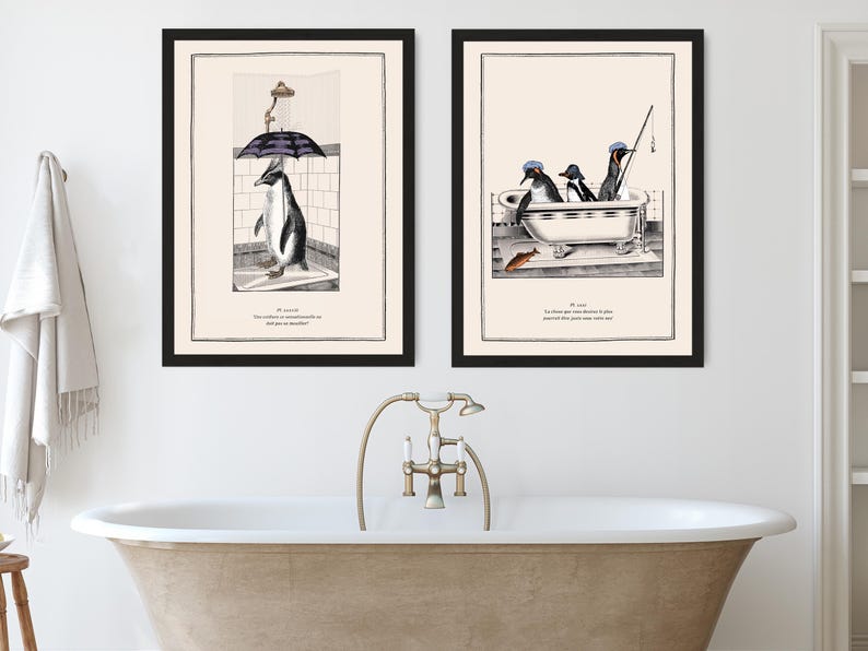 Op de afbeelding: Twee ingelijste kunstprints met pingu&iuml;n illustraties. E&eacute;n toont een pingu&iuml;n in de douche met een paraplu, de andere toont pingu&iuml;ns in een badkuip die aan het vissen zijn. Beide prints hebben zwarte lijsten en tekst onderaan.