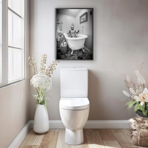 May include: A black and white photograph of a robot taking a bath in a white bathtub. The robot is sitting in the bathtub with its arms crossed. The photograph is framed and hanging on a wall in a bathroom.