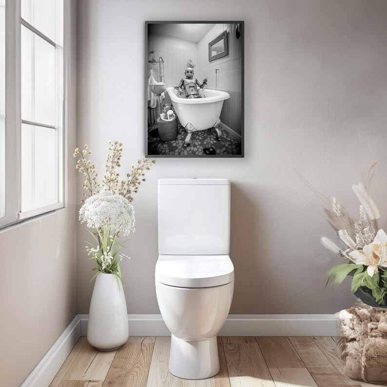 May include: A black and white photograph of a robot taking a bath in a white bathtub. The robot is sitting in the bathtub with its arms crossed. The photograph is framed and hanging on a wall in a bathroom.