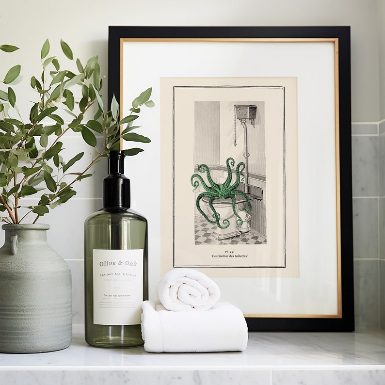 Puede incluir: Una ilustraci&oacute;n enmarcada de un pulpo en un inodoro con el texto "Pl. 331. Cachemire des toilettes". La ilustraci&oacute;n es en blanco y negro con un pulpo verde. El marco es negro con un borde dorado. Hay una botella de vidrio verde con una bomba de mano negra y una etiqueta blanca que dice "Olive & Oak" y un jarr&oacute;n de cer&aacute;mica verde con una rama de hojas verdes.