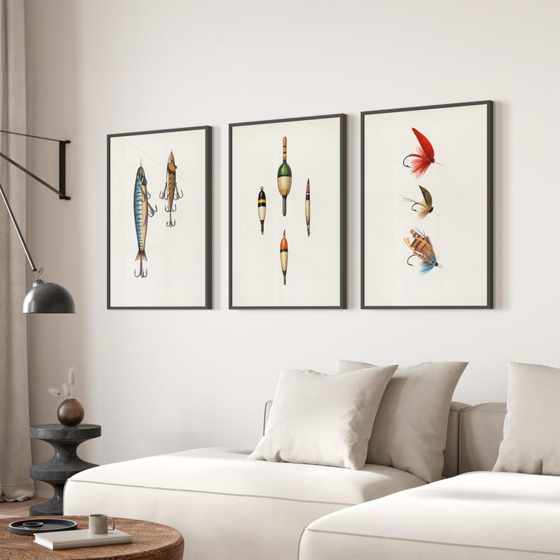 May include: Three framed art prints featuring vintage fishing lures and bobbers. The prints showcase detailed illustrations of various fishing tackle, including colorful lures and bobbers, set against a white background. The frames are black, and the artwork is displayed in a living room setting.