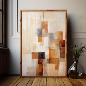 Può includere: Stampa artistica astratta in una cornice di legno. L'opera presenta un design geometrico con forme rettangolari in tonalità di marrone, grigio e arancione su uno sfondo crema. L'arte incorniciata è esposta su un pavimento in legno.