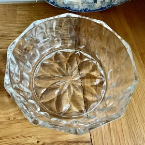 Könnte beinhalten: Eine klare Glasschüssel mit einem Sternmuster auf dem Boden. Die Schüssel hat einen gewellten Rand und ist aus klarem Glas.