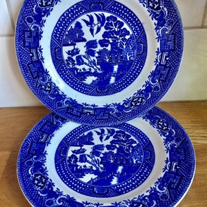 Op de afbeelding: Twee blauwe en witte borden met wilgenmotief, gestapeld op elkaar. De borden hebben een blauw en wit ontwerp met een wilg, een brug en een pagode.