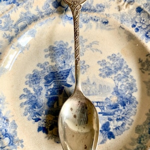 Op de afbeelding: Een zilveren lepel met een rond, versierd handvat met een portret van koningin Elizabeth II en de inscriptie "Coronation of Queen Elizabeth II 1953".