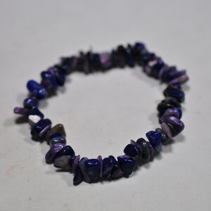 May include: A purple and blue gemstone bracelet made of small, irregular shaped stones.