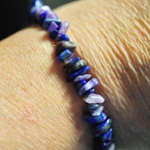 May include: A bracelet made of purple and blue gemstone beads. The beads are irregularly shaped and have a polished finish.