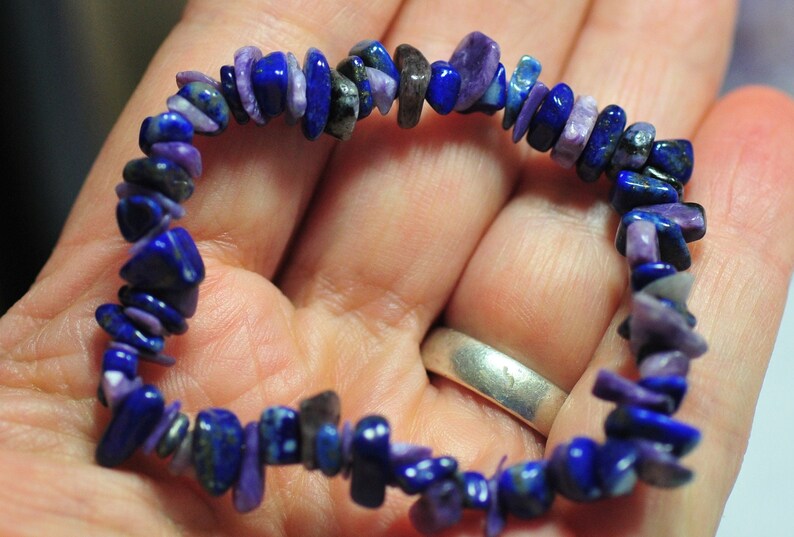 May include: A purple and blue gemstone bracelet made of small, irregular shaped chips. The bracelet is made of natural stones and is a beautiful example of handmade jewelry.