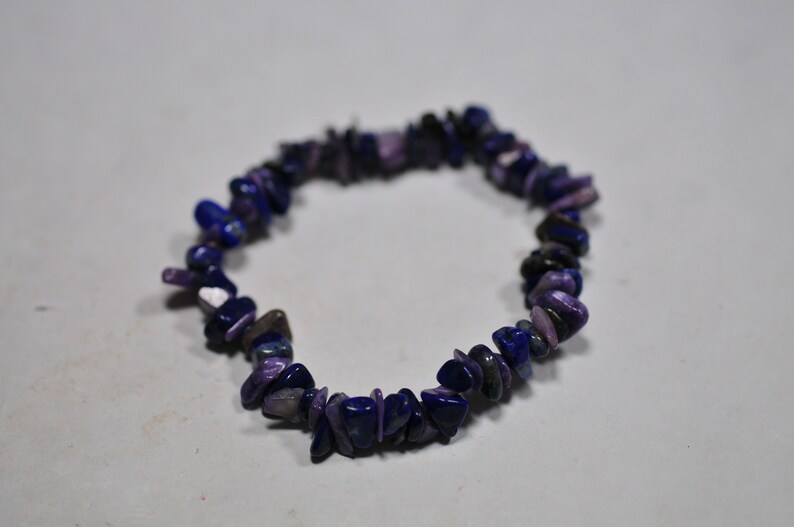 May include: A purple and blue gemstone bracelet made of small, irregular shaped stones.