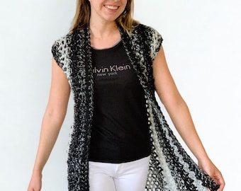 Peut inclure: Un gilet sans manches en crochet ouvert sur le devant, présentant un motif varié de fils noirs, gris et blancs. Le vêtement a une silhouette longue et droite avec une construction en maille lâche et texturée qui descend jusqu'aux cuisses.