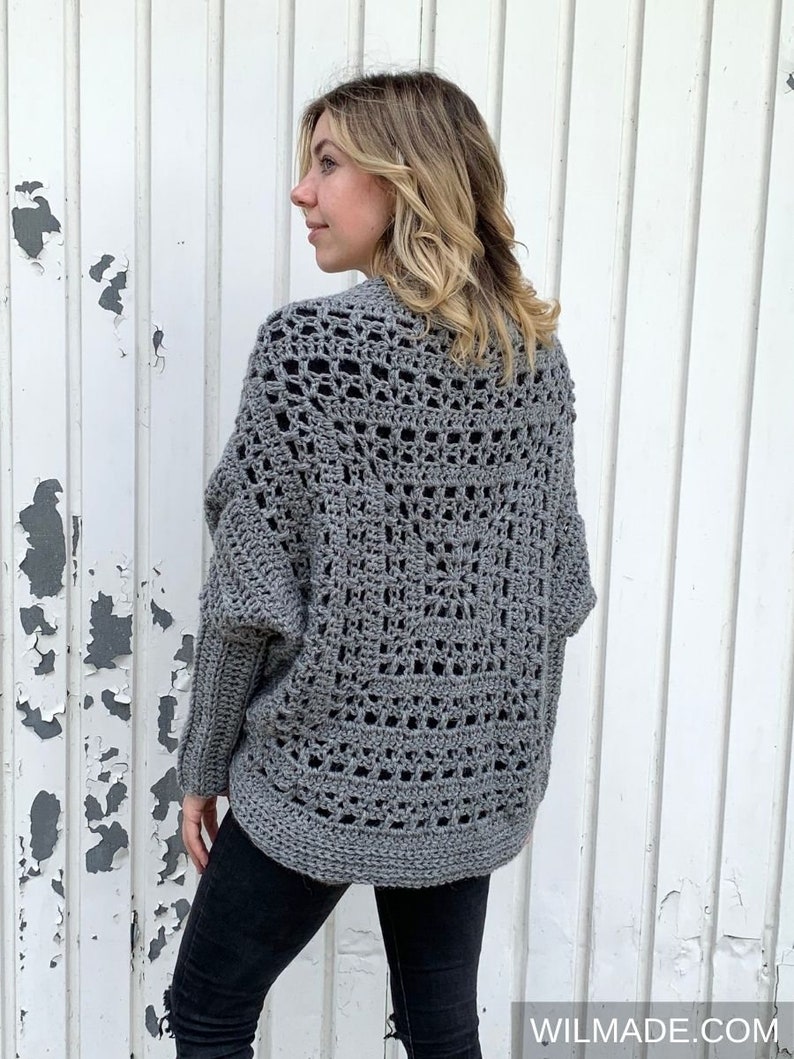 May include: A gray crochet cardigan with a lacy pattern. The cardigan has long sleeves and a loose fit.