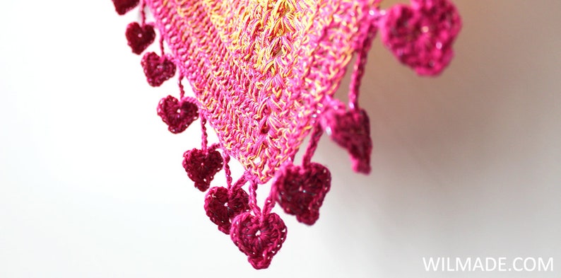 May include: A pink and yellow crocheted shawl with a heart-shaped fringe.