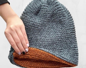 May include: A grey knitted beanie with a brown fleece lining. The beanie is folded down to show the lining.