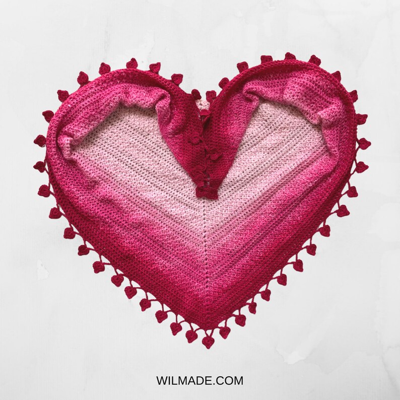 May include: A pink and red crocheted heart-shaped shawl with a scalloped edge.