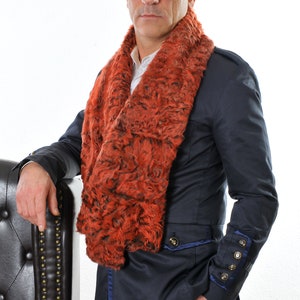 May include: A burnt orange and black faux fur scarf worn over a navy blue jacket with gold buttons and blue trim. The person is also wearing blue jeans and sunglasses. The scarf is a striking accessory.