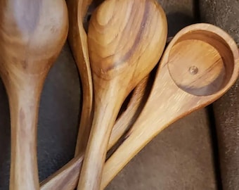 May include: A collection of wooden spoons with varying bowl shapes and handle designs. The spoons are crafted from light brown wood, showcasing the natural grain patterns. One spoon has a round bowl, while others have oval shapes, suggesting their use in cooking and serving.