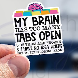 May include: A white sticker with a colorful brain graphic and the text "MY BRAIN HAS TOO MANY TABS OPEN 5 OF THEM ARE FROZEN & I HAVE NO IDEA WHERE THE MUSIC IS COMING FROM".