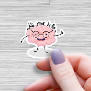 May include: A pink cartoon brain wearing glasses and giving a thumbs up. The brain has a smiling face and is standing on a white background. The text "kiss your brain" is written above the brain.