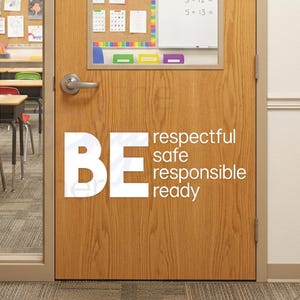 May include: A light oak wood door with a rectangular glass window and a silver lever handle. The door features white vinyl lettering that reads: BE respectful, safe, responsible, ready. The door is set in a hallway with other doors and lockers.