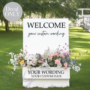 May include: White welcome sign with black text that reads "WELCOME your custom wording". The sign is decorated with a floral arrangement in a white planter. The planter has black text that reads "YOUR WORDING YOUR CUSTOM DATE".