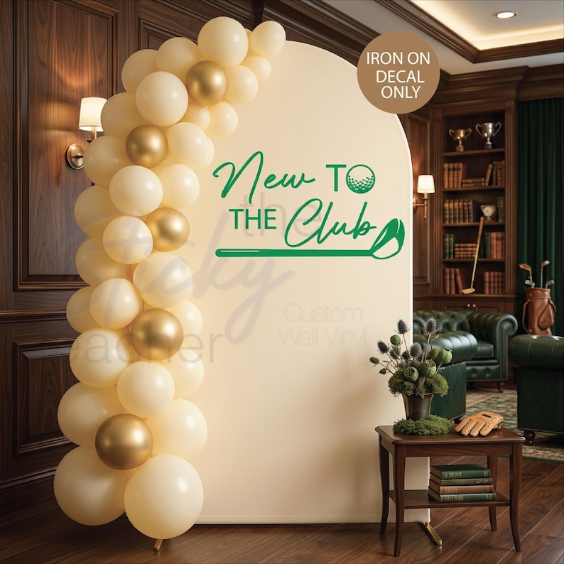 Puede incluir: Un tel&oacute;n de fondo color crema con el texto "New to the Club" en verde, con un dise&ntilde;o de pelota y palo de golf. Un arco de globos crema y dorados enmarca el tel&oacute;n de fondo. Las palabras "Iron on decal only" est&aacute;n en un c&iacute;rculo.