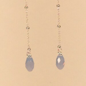May include: A pair of silver chain earrings with light blue teardrop-shaped crystal beads.