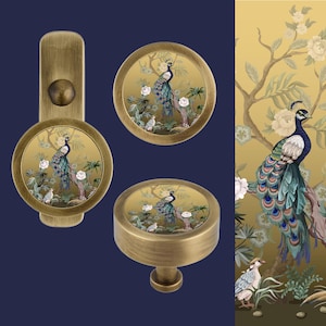 May include: Set of three brass cabinet knobs with a peacock design. The knobs feature a round base with a raised edge and a circular top with a peacock design. The peacock is depicted in shades of blue, green, and gold against a gold background.