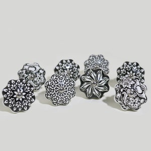 May include: Eight black and white ceramic drawer knobs with floral designs.