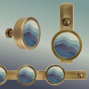 May include: Brass hooks with a blue and green abstract wave design. The hooks are round and have a decorative knob on the top. The hooks are attached to a brass bar.