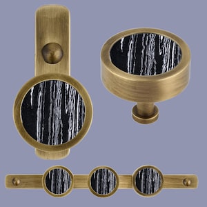 May include: Set of antique brass cabinet knobs and drawer pulls with black and white marble inlays. The knobs are round and the pulls are rectangular with three knobs.