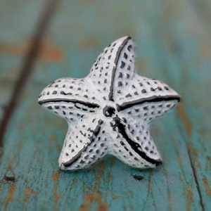 May include: White ceramic starfish with black outlines, a decorative accent for a nautical themed home.