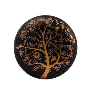 May include: Black round wooden knob with a gold tree design. The tree is decorated with small flowers and birds.
