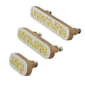 May include: Three oval-shaped drawer pulls of varying lengths, each featuring a natural wood base and a white front face with a yellow floral vine pattern. Each pull includes a metal mounting screw and washer extending from the back side.