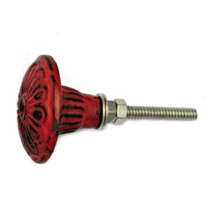 May include: Red metal cabinet knob with a decorative floral design and a silver screw.