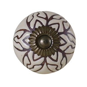 May include: White ceramic knob with a brown floral design and a gold metal screw. The knob is round and has a raised design.