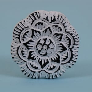 May include: White ceramic knob with a black floral design. The knob has a raised, detailed pattern.
