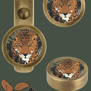 May include: Three brass cabinet knobs with a round design. Each knob features a colorful illustration of a jaguar in a jungle setting.