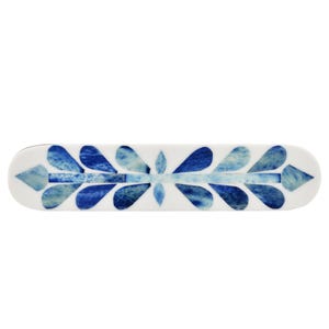 May include: A rectangular hair barrette with rounded ends featuring a white base and a symmetrical inlay pattern of blue, leaf-shaped segments arranged in a repeating design along the center, creating a distinct contrast between the white and blue.