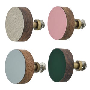 May include: Four circular cabinet knobs featuring dark brown wood sides and flat front faces in beige fabric texture, solid pink, solid light gray, and solid dark green. Each knob includes a brass-toned metal mounting bolt with a washer and nut.
