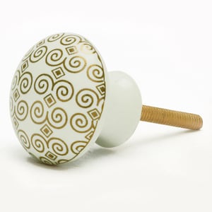 May include: White ceramic cabinet knob with a gold swirl and square pattern.