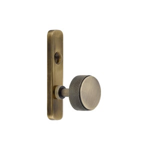 May include: Antique brass door handle with a textured, round knob and a rectangular backplate. The handle has a vintage aesthetic, with a warm, metallic finish. The knob features a crosshatch pattern for grip.