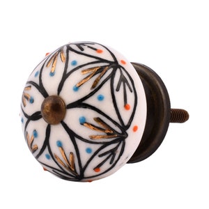 May include: White ceramic knob with a black and gold floral design. The knob has a brass base and screw.