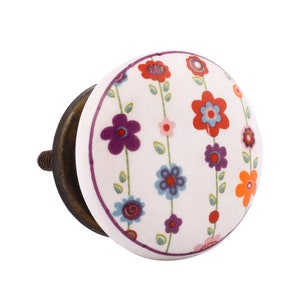 May include: White ceramic knob with a floral design featuring purple, red, orange, and blue flowers on a white background. The knob has a brass screw.